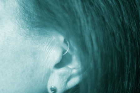 Deaf senior citizen lady wearing modern digital high technology hearing aid in ear.の写真素材