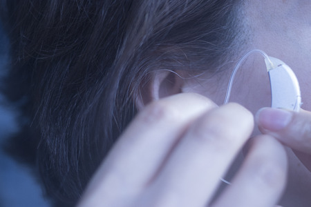 Deaf middle aged lady wearing modern digital high technology hearing aid in ear.の写真素材