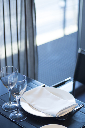 Restaurant cafe bar in luxury hotel with place settings for breakfast, lunch and dinner with wine water glasses and plates.の写真素材