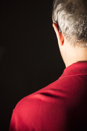 Deaf senior citizen man wearing modern digital high technology hearing aid in ear.