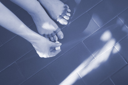 Young woman with silicone toe separator to separate toes to pedicure and paint or file toenails.の写真素材