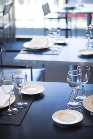 Restaurant cafe bar in luxury hotel with place settings for breakfast, lunch and dinner with wine water glasses and plates.の写真素材