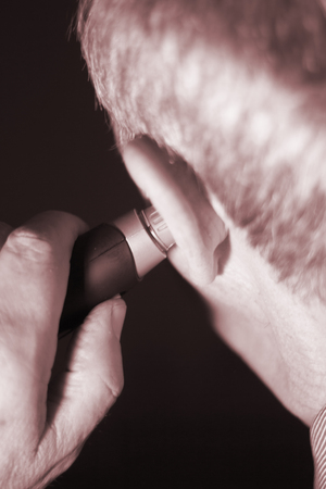 Senior citizen man cutting inner ear hair with electric cutter.の写真素材