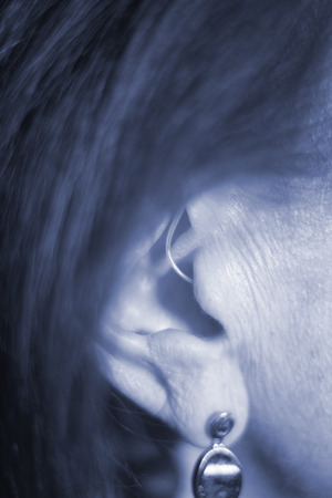 Deaf senior citizen lady wearing modern digital high technology hearing aid in ear.の写真素材