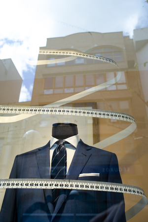 Tailor's shop window made to measure tailored suit store mannequin with formal shirt and tie with measuring tape.の写真素材