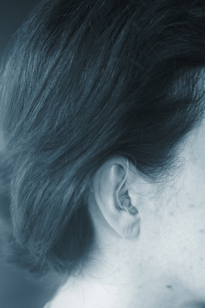 Deaf middle aged lady wearing modern digital high technology hearing aid in ear.の写真素材