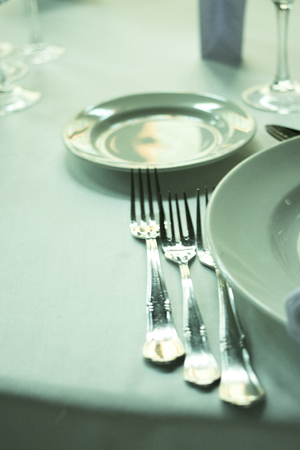 Wedding reception banquet dinner party table place settings set in luxury hotel venue.