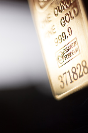 Fine solid gold 999.9 one ounce bullion ingot precious metals bar closeup isolated photo.
