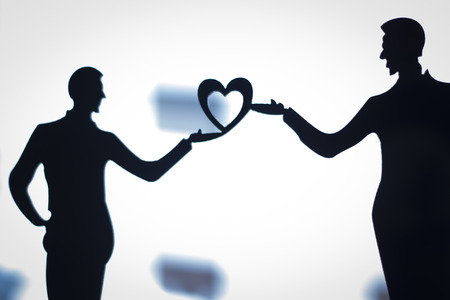 Gay LGBT wedding couple grooms holding hands with love heart shape dancing happy cake topper.の写真素材
