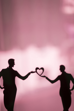 Gay LGBT wedding couple grooms holding hands with love heart shape dancing happy cake topper.の写真素材
