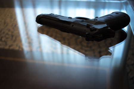 Automatic pistol gun on glass tableの写真素材