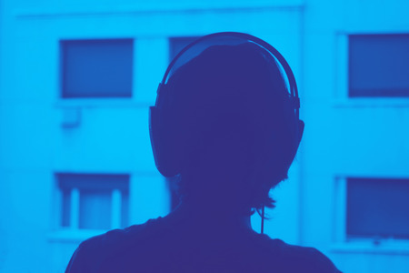 Female DJ deejay woman wearing closed headphones listening to music in artistic photo.