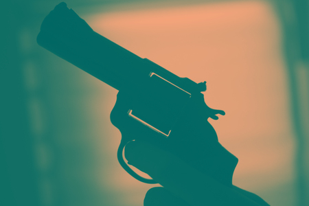 Pistol automatic handgun weapon in silhouette in hand of killer atmospheric dark dramatic photo.の写真素材