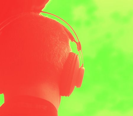 DJ deejay producer wearing closed headphones listening to music in artistic photo.