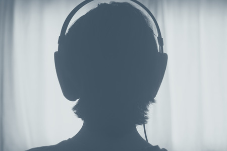Female DJ deejay woman wearing closed headphones listening to music in artistic photo.