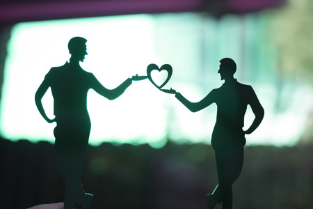 Gay LGBT wedding couple grooms holding hands with love heart shape dancing happy cake topper.の写真素材