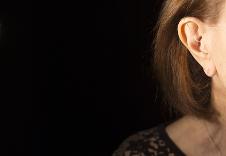 Deaf senior citizen lady wearing modern digital high technology hearing aid in ear.の写真素材