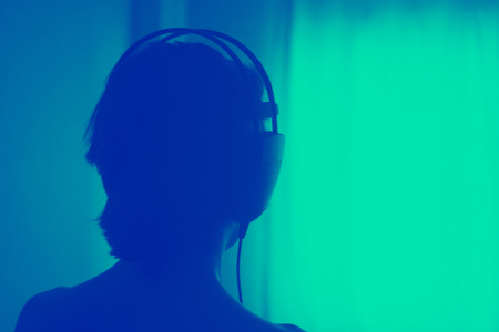 Female DJ deejay woman wearing closed headphones listening to music in artistic photo.