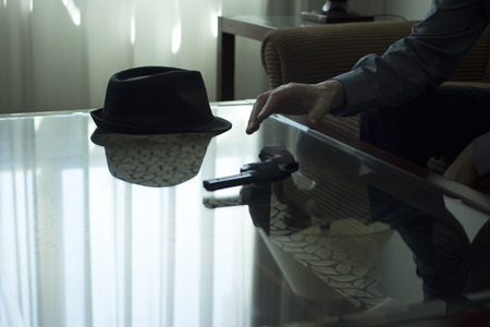 Automatic pistol gun on glass table in bedroom in luxury hotel in silhouette with reflection of window light.の写真素材