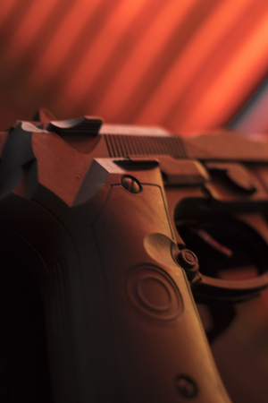 Pistol automatic handgun weapon on table in hotel bedroom in atmospheric dark dramatic photo.