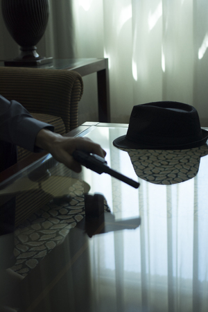 Automatic pistol gun on glass table in bedroom in luxury hotel in silhouette with reflection of window light.の写真素材