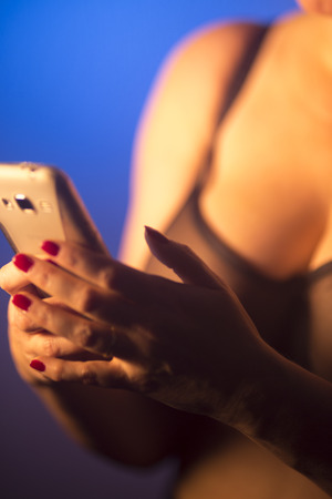 Sexy very big breasts busty lady using mobile cell phone in erotic lingerie underwear.の写真素材