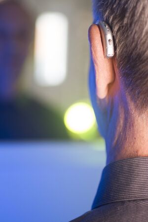 Caucasian white old aged man wearing modern digital hearing aid in ear with grey hair.の写真素材