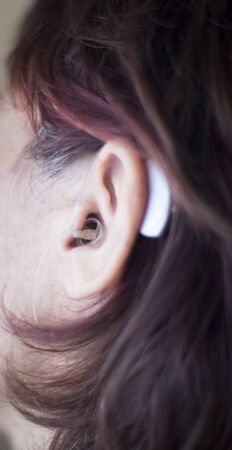 Deaf middle aged lady wearing modern digital hearing aid.