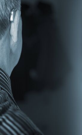 Caucasian white old aged man wearing modern digital hearing aid in ear with grey hair.の写真素材