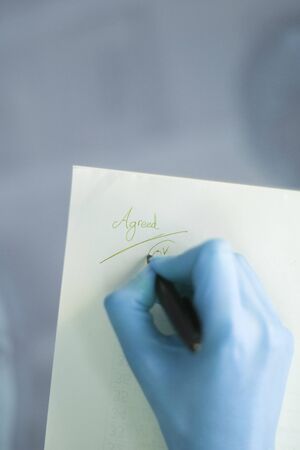 Young lady writing on paper with pencil in hand on table.の写真素材