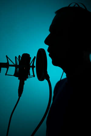 Voiceover artist voice actor in vocal recording studio with larg diaphragm microphone and antipop shield.の写真素材