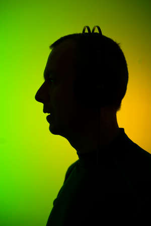 Dj deejay electronic wearing music headphones with coloured lights plain studio background.の写真素材