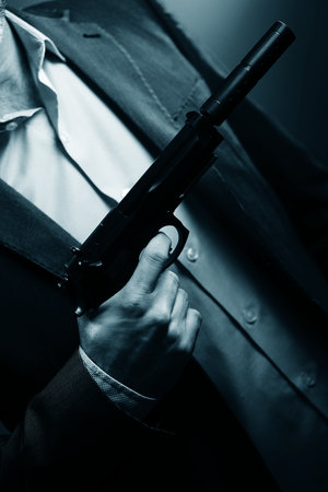 Well dressed male secret agent detective spy wearing suit and tie holding automatic pistol.の写真素材