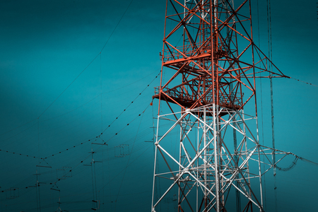 Engineering progress for communication structures. Massive, red and white power pylon on blue sky, providing energy and telephone connections across Italy.の写真素材
