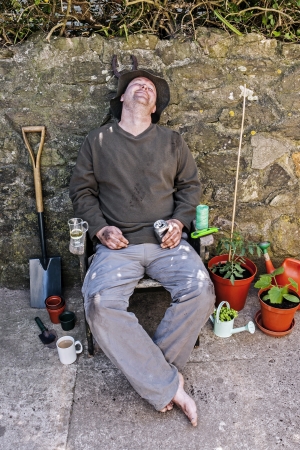 Male gardener happy and asleep in garden chair amongst his tools after gardening の写真素材