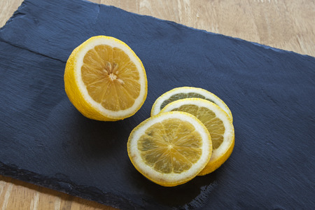 Lemon and lemon slices, juicy and ripe, on slate の写真素材