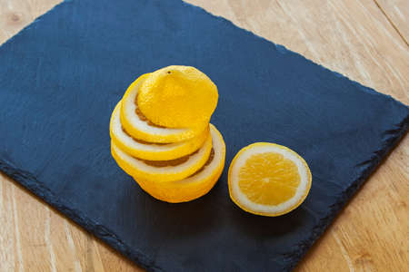 Lemon and lemon slices, stacked on top of each other, juicy and ripe, on slate - with copy   text space の写真素材