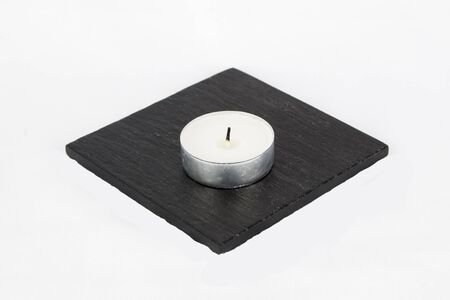 T light candle, unlit, on stone coaster, with wick, isolated on white background.の写真素材
