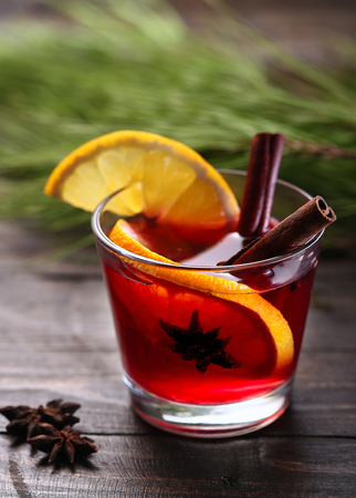 Mulled wine with spices and Christmas tree on wooden backgroundの写真素材
