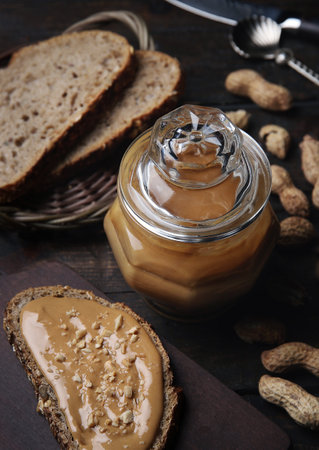 Organic Peanut Butter in Glass Jar with Peanuts in Shell on Wooden Background. Healthy Breakfast Vegetarian Food Concept.の写真素材