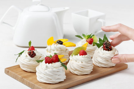 Homemade mini pavlova cakes with whipped cream and fresh berries on light backgroundの写真素材