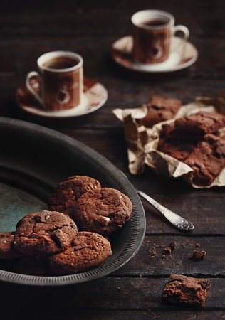Homemade chocolate cookies and 2 cups of coffee on a dark wooden tableの写真素材