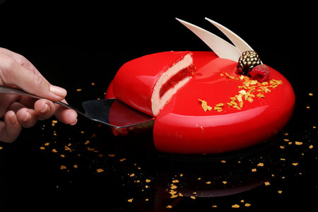 Cake with berry mousse in a mirror red glaze decorated with berries and white chocolate. On black background.の写真素材