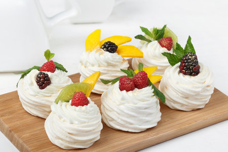 Homemade mini pavlova cakes with whipped cream and fresh berries on light backgroundの写真素材