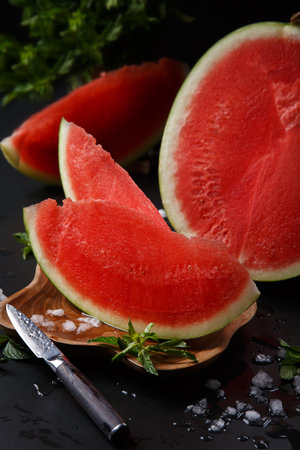 Close-up of a cut round ripe watermelon on a black background.の写真素材