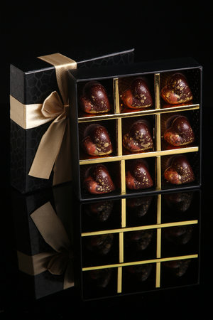Heart shaped painted luxury handmade bonbons in a gift box on a black background. Chocolates for Valentine's Day.の写真素材
