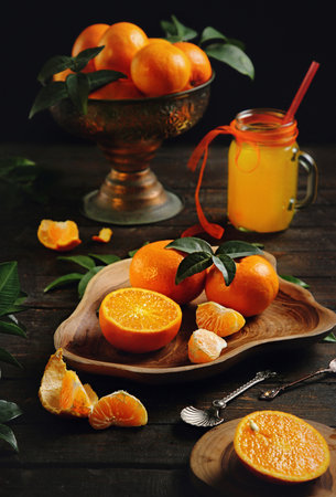 Juicy orange tangerines and tangerine juice in a jar on an old wooden tableの写真素材