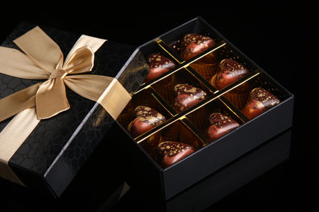 Heart shaped painted luxury handmade bonbons in a gift box on a black background. Chocolates for Valentine's Day.の写真素材