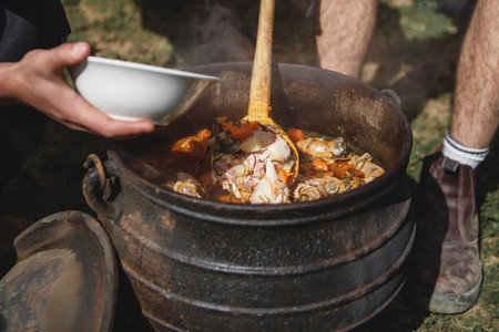 Cooking stew in cast iron cauldron outdoorsの写真素材