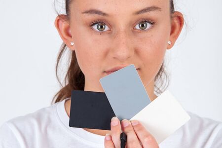 Eighteen 18 precent grey gray card, white and black card used for photography with young girl in background on white background in studio suitable for websites, editorial or brochuresの写真素材